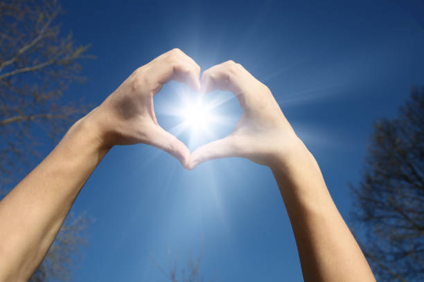 istock Hand shaped heart against sunset 1204707339
