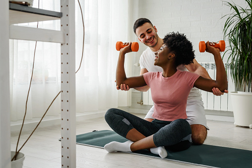 Young smiling multi ethnic couple exercising together at home