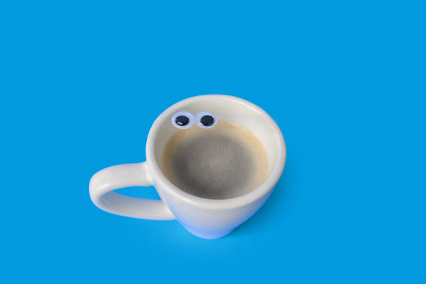 istock Anthropomorphic Face with Googly Eyes on a Cup of Espresso Coffee on a Colored Background 1204709609
