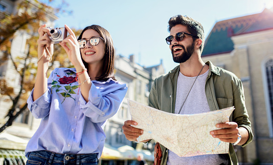 Beautiful couple on vacation using the city map while exploring the locations. Concept of tourism