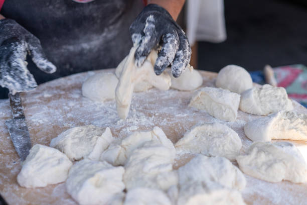 istock Chef in black gloves cuts raw dough into pieces make pizza Patties bread. 1204717493