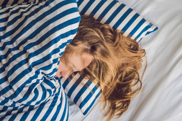 belle jeune femme se couchant dans le lit et dormant. ne pas obtenir assez concept de sommeil - beauty beautiful tired blond hair photos et images de collection