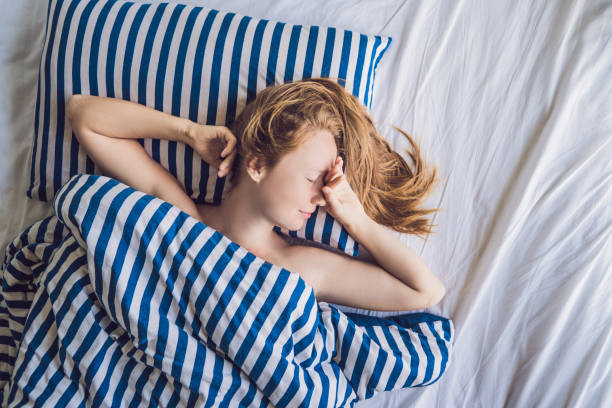 belle jeune femme se couchant dans le lit et dormant. ne pas obtenir assez concept de sommeil - beauty beautiful tired blond hair photos et images de collection