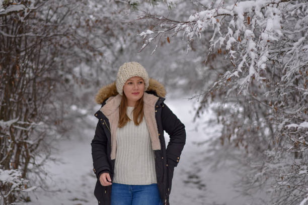 istock Young woman walking through snow covered forest 1204719882