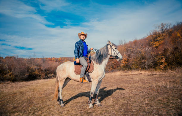 młody człowiek cieszący się jazdą konną - cowboy horseback riding nature blue zdjęcia i obrazy z banku zdjęć