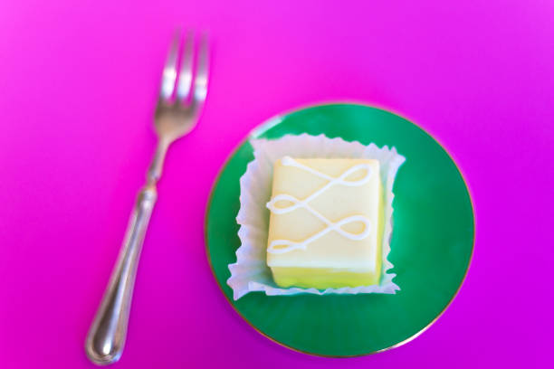 フォーク、ピンクの背景とグリーンプレート上のプチフォー/ケーキ - petit four ストックフォトと画像