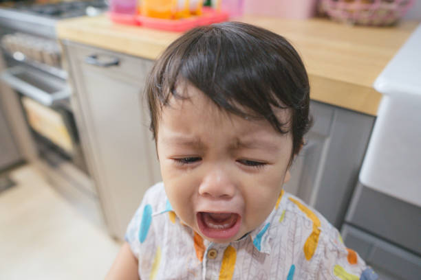 Crying toddler in the kitchen stock photo