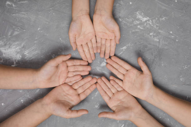istock childrens hands together in a circle on gray 1204740964