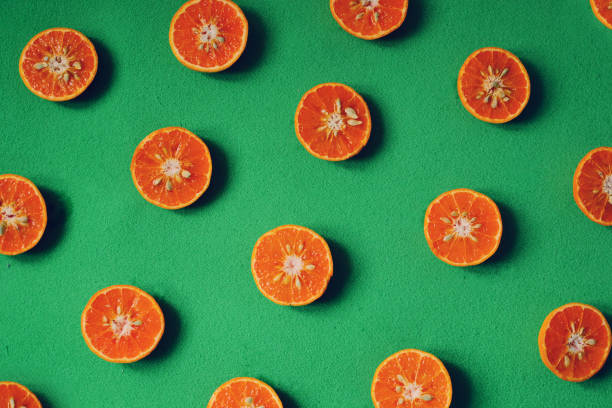 istock Cut fresh oranges on red plate and green background 1204749901