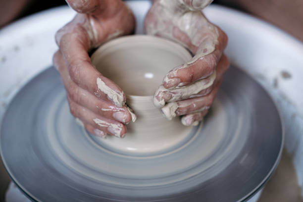 istock Female potter hands working with clay in workshop. White desk on background 1204750889