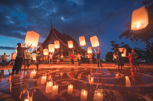 Ubon Ratchathani , Thailand - November 25, 2015 ; Group of young people releasing lanterns in Sirindhorn Wararam Phu Prao is public Temple (Wat Phu Prao) at evening,a glow of the sculpture of the Kalpapruek