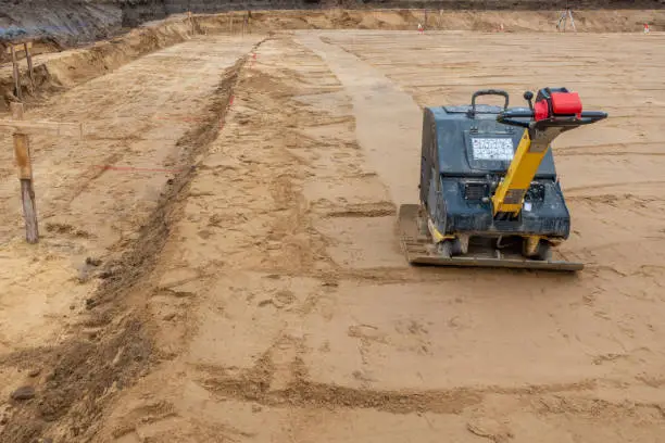 on a building site there is a vibrator preparing the ground for foundations