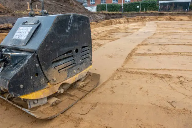 on a building site there is a vibrator preparing the ground for foundations