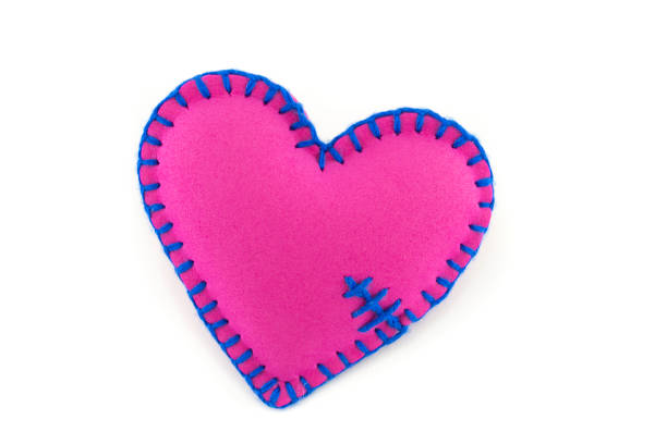 istock Handmade pink stitched toy heart on white 1204758325