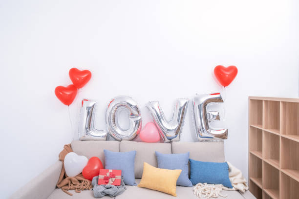 foil palloncini d'amore e regali su un divano con parete bianca sullo sfondo per san valentino, sorpresa festa della mamma. - cushion pillow heart shape multi colored foto e immagini stock