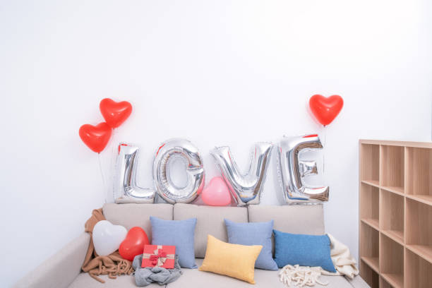 folia miłość balony i prezenty na kanapie z białą ścianą w tle na walentynki, niespodzianka dzień matki. - cushion pillow heart shape multi colored zdjęcia i obrazy z banku zdjęć
