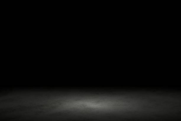 istock Light shining down on black marble floor in dark room with copy space, abstract background 1204759715