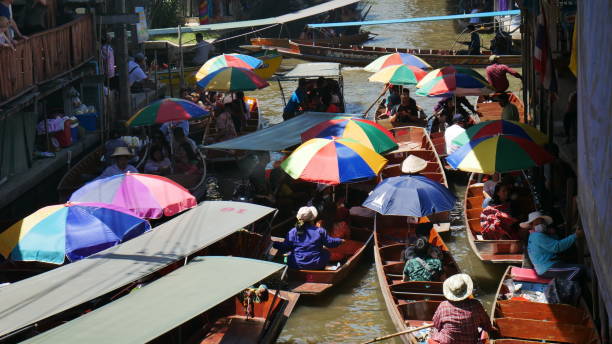 Over-crowded tourists at Floating Market Ratchaburi, Thailand-July 20, 2019: Over-crowded tourists at Damnoen Saduak floating market, Thailand. Vendors selling food and tourists taking the cultural tour on the boat around the canal. ratchaburi province stock pictures, royalty-free photos & images