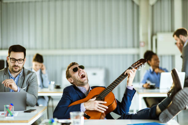 istock Happy businessman singing and playing a guitar in full office. 1204773628