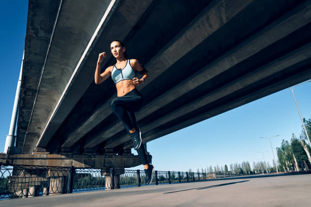 istock Sporty woman running outdoors under city bridge 1204779413