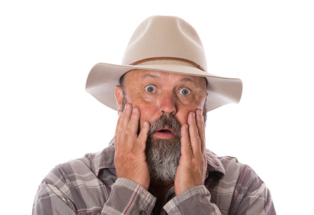 Studio portrait of a man wearing a white cowboy hat, pointing his finger gun at the camera