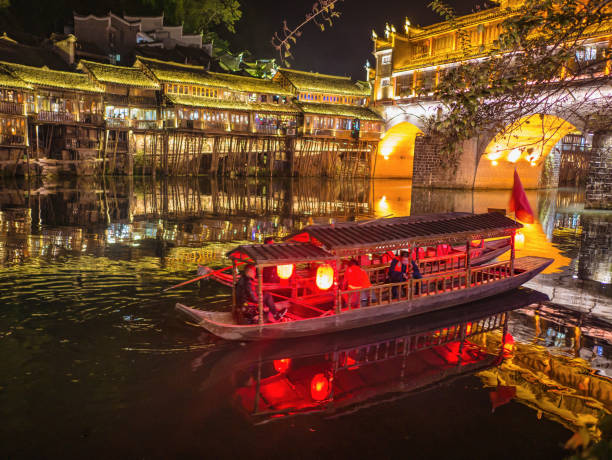 Unacquainted tourist sightseeing fenghuang old town in the night by boat in the river.phoenix ancient town or Fenghuang County is a county of Hunan Province, China fenghuang,Hunan/China-16 October 2018:Unacquainted tourist sightseeing fenghuang old town in the night by boat in the river.phoenix ancient town or Fenghuang County is a county of Hunan Province, China fenghuang county photos stock pictures, royalty-free photos & images