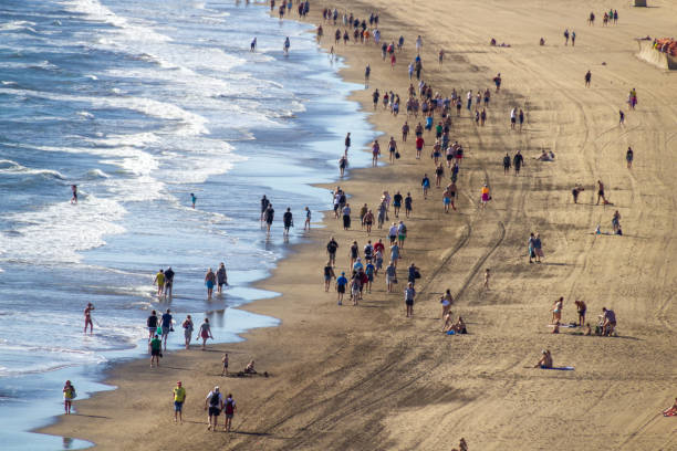 istock Tourists walk over the beach 1204789279