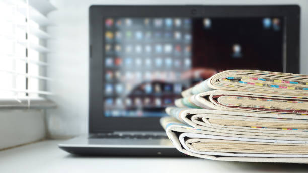 istock Open Laptop with Newspapers Stacked on its Keyboard 1204790481