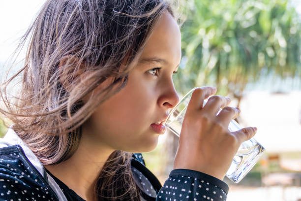 istock Tween girl drinks glass of water 1204793465