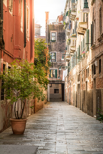 Morning sun hits a small alley in the old town of Venice island, Veneto, Italy. Typical buildings form the world heritage site.