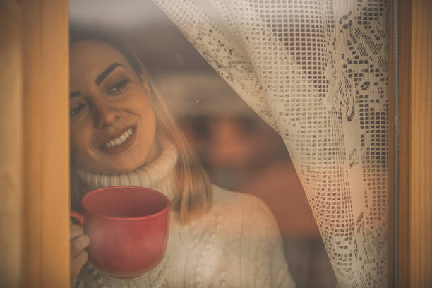 istock Attractive blond woman enjoying view through the window 1204794454