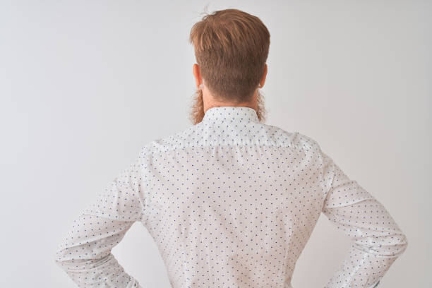 Young redhead irish businessman standing over isolated white background standing backwards looking away with arms on body