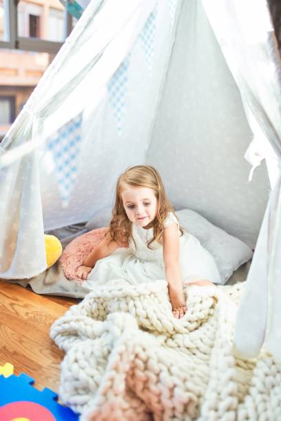 istock Adorable blonde toddler playing sitting on blanket inside tipi at kindergarten 1204796343