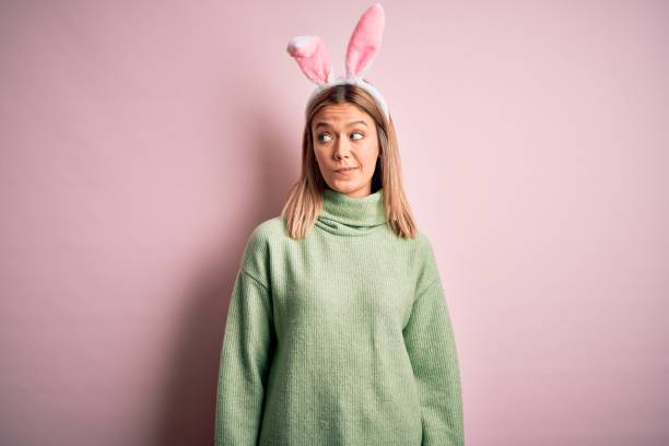 istock Young beautiful woman wearing easter rabbit ears standing over isolated pink background smiling looking to the side and staring away thinking. 1204797171