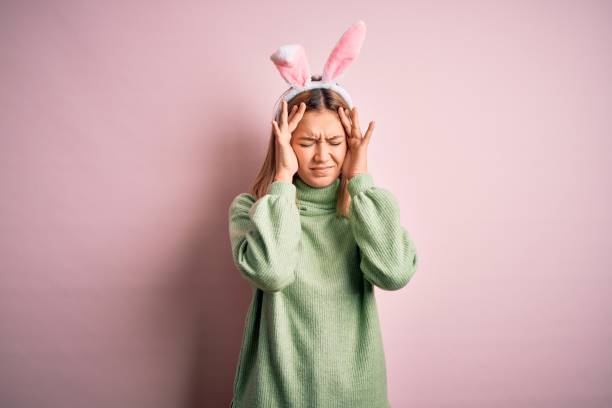istock Young beautiful woman wearing easter rabbit ears standing over isolated pink background suffering from headache desperate and stressed because pain and migraine. Hands on head. 1204797736