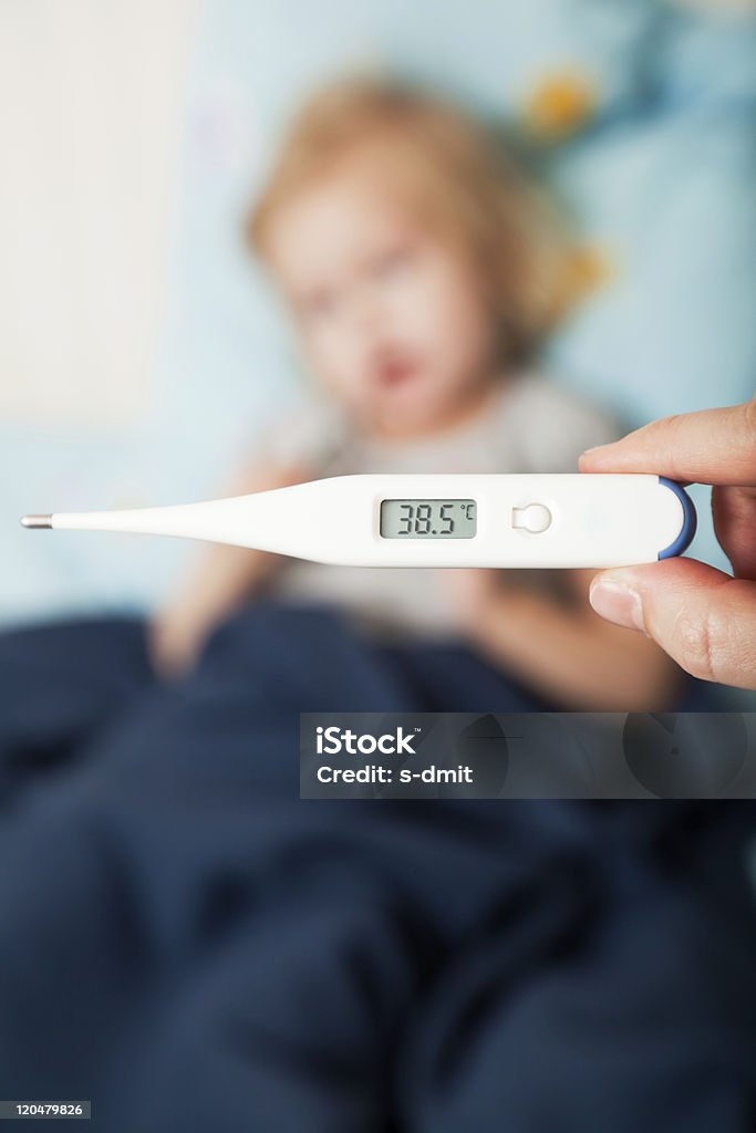 mother measures the temperature of her daughter  Bed - Furniture Stock Photo