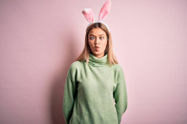 istock Young beautiful woman wearing easter rabbit ears standing over isolated pink background making fish face with lips, crazy and comical gesture. Funny expression. 1204798290