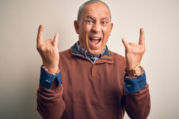 istock Senior handsome man  wearing elegant sweater standing over isolated white background shouting with crazy expression doing rock symbol with hands up. Music star. Heavy concept. 1204799221