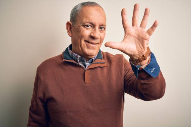 istock Senior handsome man  wearing elegant sweater standing over isolated white background showing and pointing up with fingers number five while smiling confident and happy. 1204799247