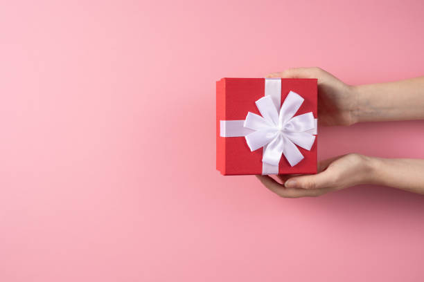 istock Valentine's Day celebration concept. A nice gift from a loved one. Box with a bow in female hands on a delicate pink background. Copy space. Flat lay. 1204799624