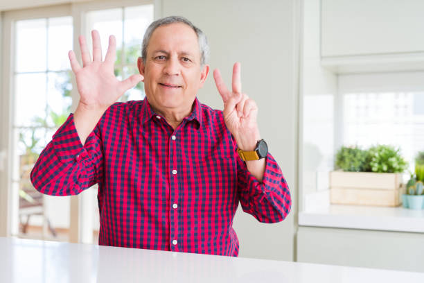 istock Handsome senior man at home showing and pointing up with fingers number seven while smiling confident and happy. 1204803776