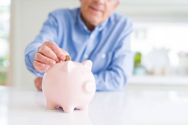 istock Man putting a coin inside piggy bank as savings smiling confident 1204803889