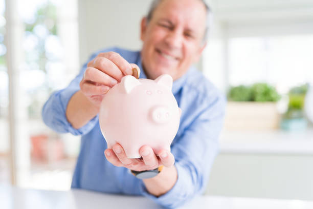 istock Man putting a coin inside piggy bank as savings smiling confident 1204803900