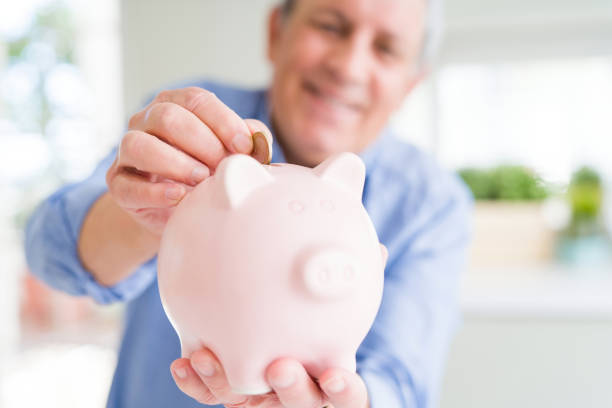 istock Man putting a coin inside piggy bank as savings smiling confident 1204803902