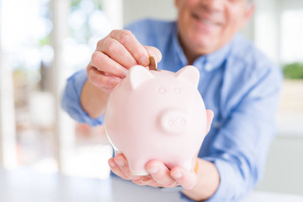 istock Man putting a coin inside piggy bank as savings smiling confident 1204803926
