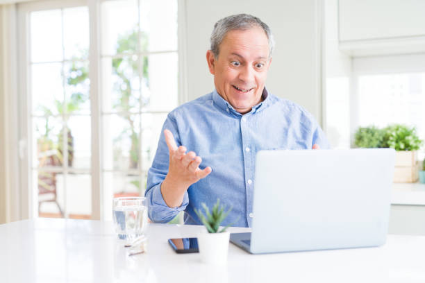 istock Handsome senior man using computer laptop working on internet very happy and excited, winner expression celebrating victory screaming with big smile and raised hands 1204803935