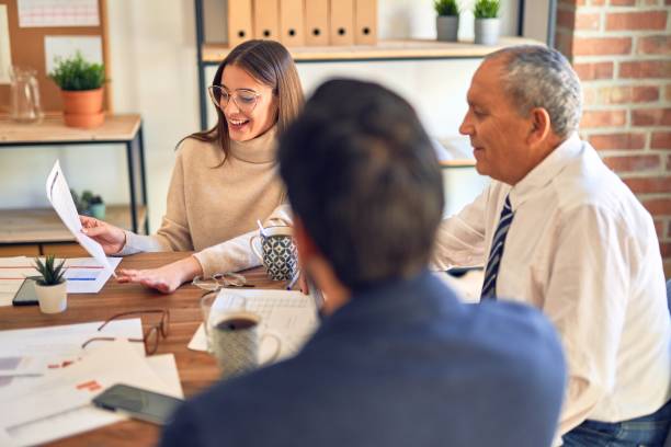 istock Group of business workers working together. Sitting on desk using laptop reading documents at the office 1204808724