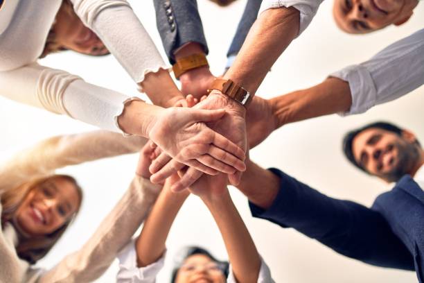 gruppo di imprenditori in piedi con le mani insieme in ufficio - teamwork foto e immagini stock