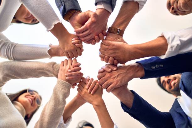 istock Group of business workers standing with hands together at the office 1204809127