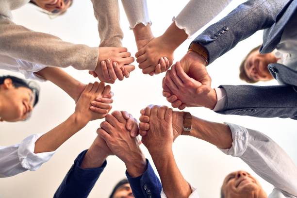 istock Group of business workers standing with hands together at the office 1204809133